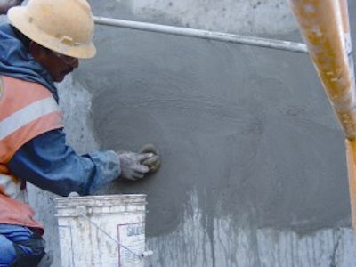 Rubbed finishes (free of bugholes) consist of either smooth-rubbed, grout-cleaned rubbed or cork-floated finishes. Here a worker is producing a grout-cleaned finish free of bugholes by rubbing a grout into the surface voids.