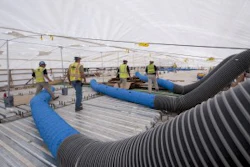 Personnel adjust the ductwork that brings cool air into the containment area. This cooling was needed to control the temperature to restrict the thermal movement of the structural steel while the pier cap concrete cured to sufficient strength.