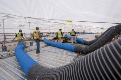 Personnel adjust the ductwork that brings cool air into the containment area. This cooling was needed to control the temperature to restrict the thermal movement of the structural steel while the pier cap concrete cured to sufficient strength.