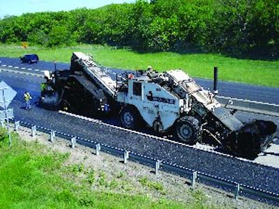 A Shuttle Buggy feeds asphalt into the Roadtec SP-200 spray paver, which is paving the driving lane on Interstate 35 in Kansas.