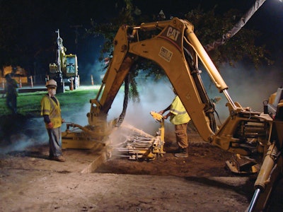 A backhoe mounted drill assembly is used to create holes for dowel bars.