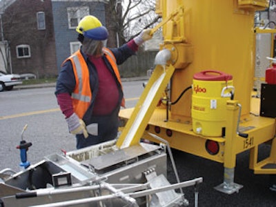 When the handliner is empty the operator returns to the melter and fills it up again. The advantage is one of productivity and efficiency as an operator or crew can put down much more material on the pavement when using melter kettles to heat it. Note the face shield.