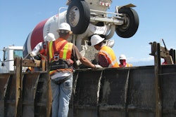 A four-man crew works quickly to pour and finish a typical parapet. One worker uses a power vibrator to consolidate the concrete for uniform density and blend the concrete together into a single solid mass.