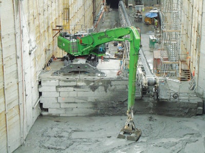 The operator of the SENNEBOGEN 870 M scoops up tailings with a custom clamshell bucket.