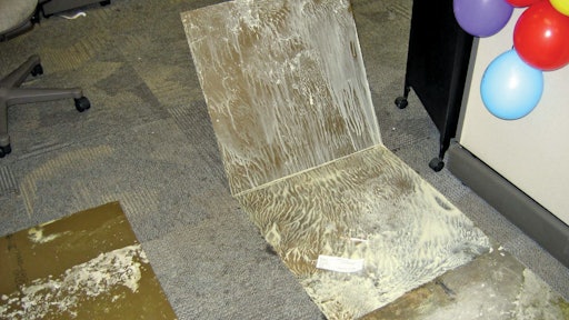 Water vapor that traveled through the concrete slab reached dew point and re-emulsified the water-based glue that once secured these carpet tiles to the concrete substrate.