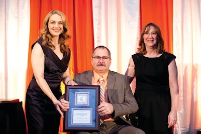 Tiffany Sewell-Howard (left), CEO of The Charles Machine Works Inc. (parent company of Ditch Witch, presents Jeff Lone (seated) of Ditch Witch Midwest, accompanied by his wife, Marsha (right), with the 2012 Service Manager of the Year Award.