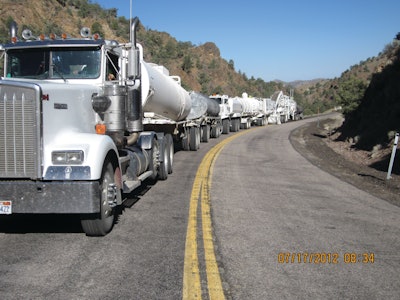 The mobile recycling train is led by a water truck towing a lime-slurry trailer. The next machine is a Roadtec RX-900 milling machine, which pulverizes the asphalt to a depth of 3 inches and conveys the material back to a Roadtec RT-500 mobile recycler.
