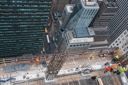 Looking down from above, workers use the top floor of the five story DOKA self-climbing deck system to erect column reinforcement.