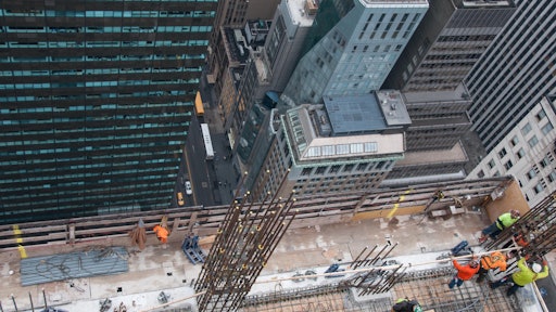 Looking down from above, workers use the top floor of the five story DOKA self-climbing deck system to erect column reinforcement.