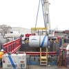 Ground level view of the excavation, showing proximity to an active rail yard, as Microtunnel machine is lowered into the shored excavation.