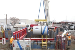 Ground level view of the excavation, showing proximity to an active rail yard, as Microtunnel machine is lowered into the shored excavation.