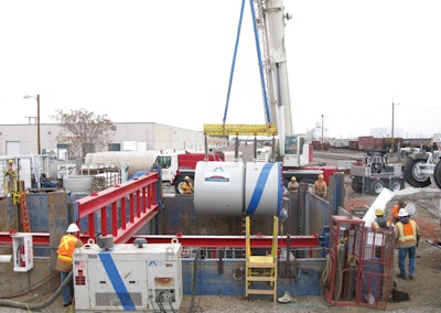 Ground level view of the excavation, showing proximity to an active rail yard, as Microtunnel machine is lowered into the shored excavation.