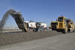 Instead of five to six haul trucks recirculating, Las Vegas Paving uses two paddle wheel scrapers to pick up windrows of RAP and deposit the material on airfield unpaved areas, where it will be compacted and used for erosion control.