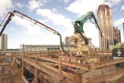 The end hose of a truck-mounted boom pump is tied directly into the pipeline below the pedestal that would deliver the concrete to the placing boom.
