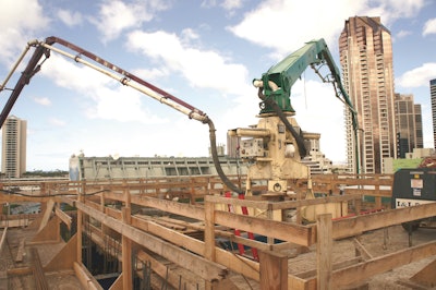 The end hose of a truck-mounted boom pump is tied directly into the pipeline below the pedestal that would deliver the concrete to the placing boom.