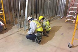 YouthBuild Boston student working with Century Dry Wall foreman laying out bottom track of wall framing for Suffolk Construction’s management offices in the Millennium Tower.