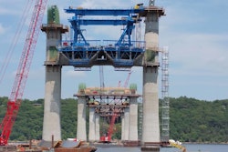 The new St. Croix River Bridge will span between Minnesota and Wisconsin near Stillwater, Minn. Shown here are the piers, cross beams, first precast segments in place, and the extra-dosed towers. The blue structure is a “segment lifter” that lifts castings into position from barges weighing as much as 180 tons.