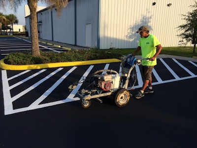 Asphalt Sealers Inc. crew member striping an American Legion Post after sealcoating.