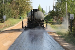 Charles E. Watts Inc.’s E.D. Etnyre & Co. distributor sprays high-float emulsion at rate of 0.395 gal per sq. yd. on Route 29 surface following reclamation by Cherokee County, AL, forces.