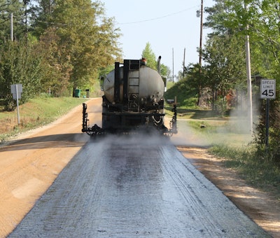 Charles E. Watts Inc.’s E.D. Etnyre & Co. distributor sprays high-float emulsion at rate of 0.395 gal per sq. yd. on Route 29 surface following reclamation by Cherokee County, AL, forces.