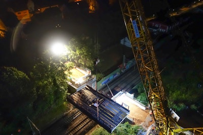 The steel bridge structure was delivered in two sections and welded on-site, resulting in a total weight of 77 tons, including the required slinging gear. After the load was meticulously rigged so that it would be perfectly balanced, the power to the overhead lines was turned off and the precision lifting started.