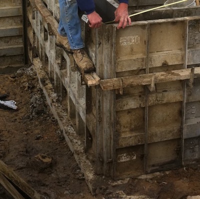 A forming crew worker checks the square on a foundation set. Variations in the actual line of the set wall forms on the footing are possible when final measurement checks are made.