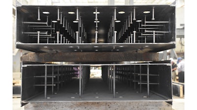 Steel plates connected by steel spacing ties are ready for the cavity to be filled with high-strength concrete. These test specimens, shown before concrete fill, have various spacing and quantities of cross ties and shear studs.