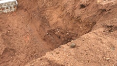 Figure 1: Residential basement excavation with over 8-ft of depth. No benching, loose soil encumbrances on the slope and spoil piles closer than 2-ft from the opening. This excavation should not be entered until corrected.