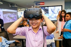 A seventh grader from DREAM tries on VR goggles in the Smart Lab during a visit to the Suffolk offices.