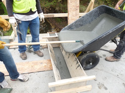 Workers are placing Ultra-high performance concrete (UHPC) on a bridge deck for the Iowa Department of Transportation. Precast panels and structurally tying the rebar together extending from the panels.