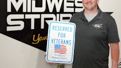 Robert Lindsay displays the first version of the sign he installs for free. A recent 'everybody' sign says 'Super Heroes Parking. Reserved for vets, active military, law enforcement, fire, EMS and search & rescue personnel. Thank you for your service.'