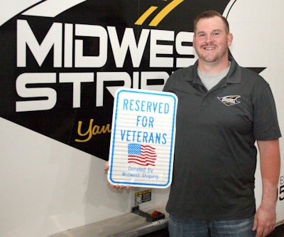 Robert Lindsay displays the first version of the sign he installs for free. A recent 'everybody' sign says 'Super Heroes Parking. Reserved for vets, active military, law enforcement, fire, EMS and search & rescue personnel. Thank you for your service.'