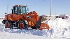 Make sure snow pusher attachments interfacing with a bucket are properly secured prior to use.