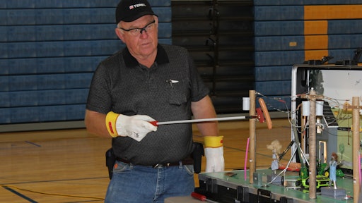 Roger Crom, retired lineman and Terex Utilities safety consultant, demonstrates how electricity in Safety Town works. The hot dog is used to mimic what happens in the human body when exposed to electricity.