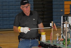 Roger Crom, retired lineman and Terex Utilities safety consultant, demonstrates how electricity in Safety Town works. The hot dog is used to mimic what happens in the human body when exposed to electricity.