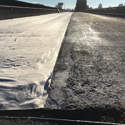 An up-close photo of a new layer of asphalt over waterproof matting. The matting keeps rain from seeping into the trestle's concrete and rebar structure.