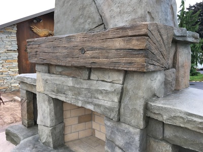 The carved stone and wood beam detailing of the fireplace complements the natural stone of the adjacent house.