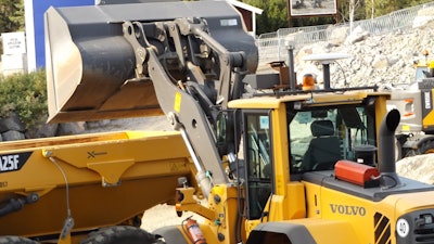 A Volvo autonomous L120 wheel loader and A25F articulated hauler carry out a loading and transport operation.