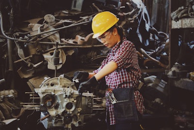 Woman Wears Yellow Hard Hat Holding Vehicle Part 1108101
