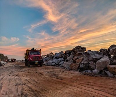 Red Dump Truck Near Filed Rocks Under Cloudy Sky 1044290