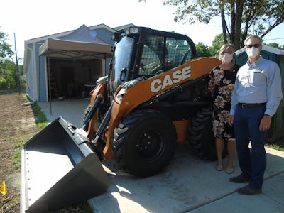 Ann Fox with Habitat and Troy Williams with CASE alongside the donated skid steer