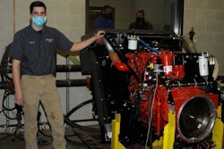 Michael J. Sormilic, an online power generation student from Southbury, Conn., who has spent much of the Fall 2020 semester learning the ins and outs of the equipment, stands alongside a Cummins crane engine donated to Pennsylvania College of Technology by Terex Corp. Behind him, in the control room of the dyno lab, are John D. Motto (left), diesel equipment technology instructor, and Chris Macdonald, assistant director of corporate relations.