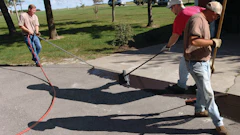Use a brush and squeegee to spread the sealcoat out on the pavement