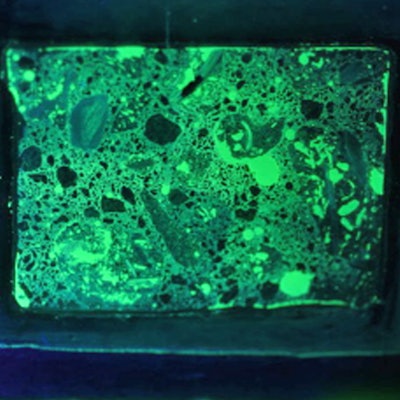 Photograph of a fluorescent thin section in UV light, which makes the concrete glow.