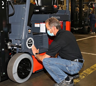 Toyota associate applies commemorative placard, completing the assembly of the milestone 750,000 forklift to roll off Toyota Material Handling's production line in Columbus, Indiana.