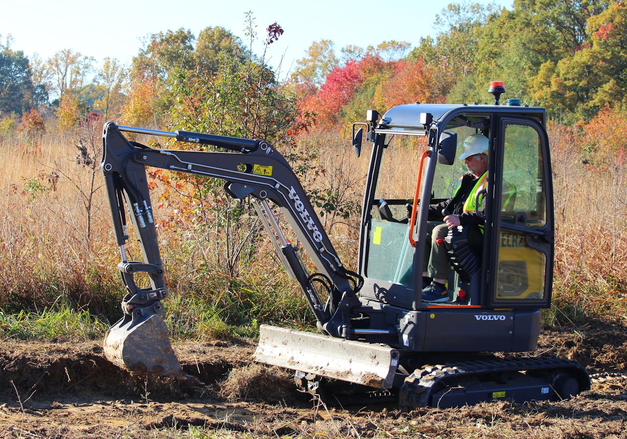 The ECR25 Electric Compact Excavator digs trenches to improve pond drainage and helps build a viewing platform over the pond.