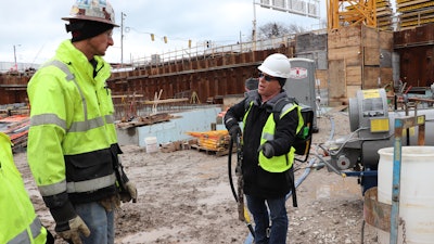 Greg Ramer (right), sales manager for Wacker Neuson explains the advantages of Wacker Neuson’s ACBe battery-powered backpack vibrator to Jeff Kremel, site superintendent for J. H. Findorff & Son, general contractor for the Couture site.