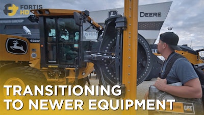 A Guy Watches A John Deere 622 Gp Motor Grader At A Heavy Equipment Expo