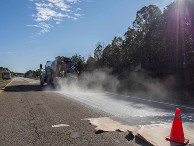 A truck applies Delta Mist to the NCAT test track. The non-toxic rejuvenator requires no pre-heating or special equipment and is applied as a milky white substance which dries clear.