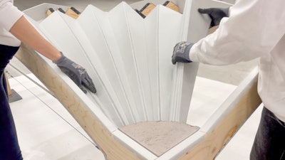 Unfold Form consists of a plywood sheet cut into individual curved strips with textile layers applied to one side to connect them. The plywood strips can be unfolded like a fan on site, causing them to bend into shape.